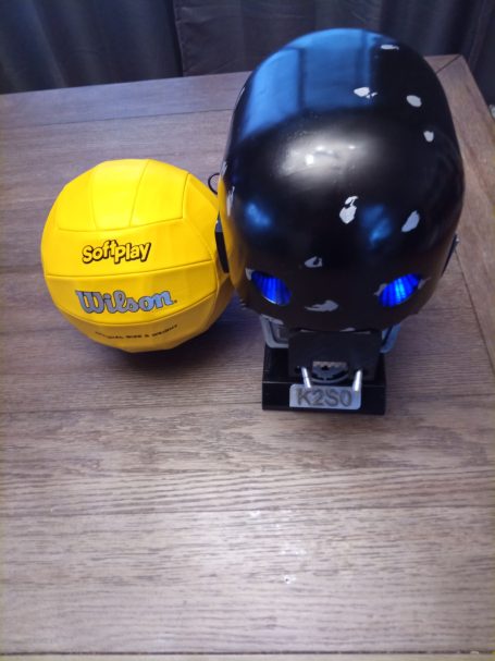 A black skull and a yellow ball with the name "Wilson" on a wooden table.